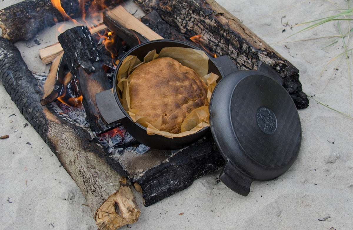 Støbejernsgryde over bål på en strand