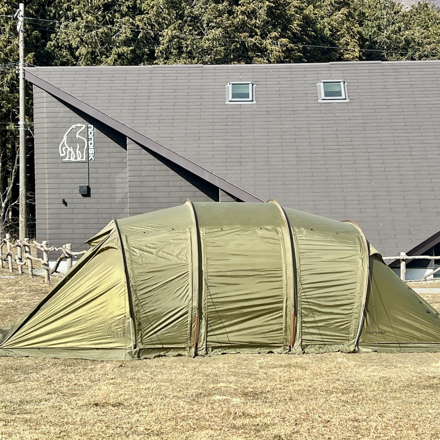 Green tent in front of a building with a logo on a clear day