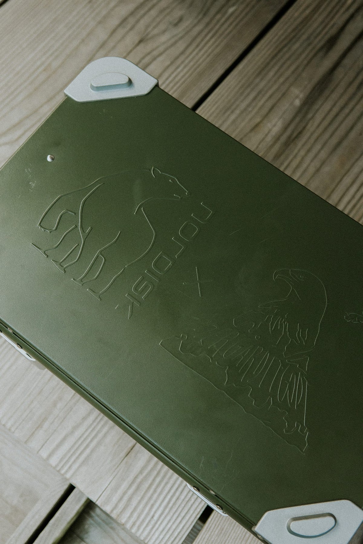 Grøn opbevaringsboks med Nordisk og ørn logo på træbaggrund