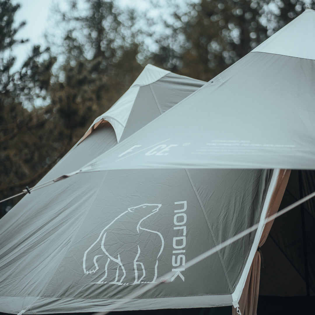 Nordisk tent with bear logo in a forest setting