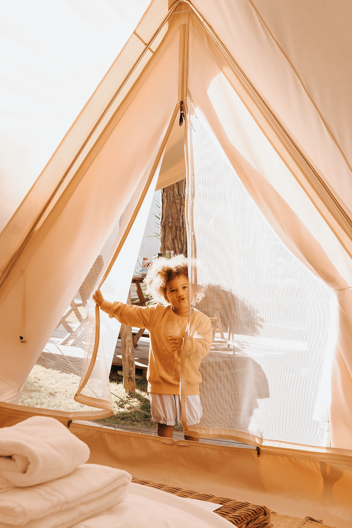 Smilende barn kigger ud fra luksuriøst glamping telt i naturen