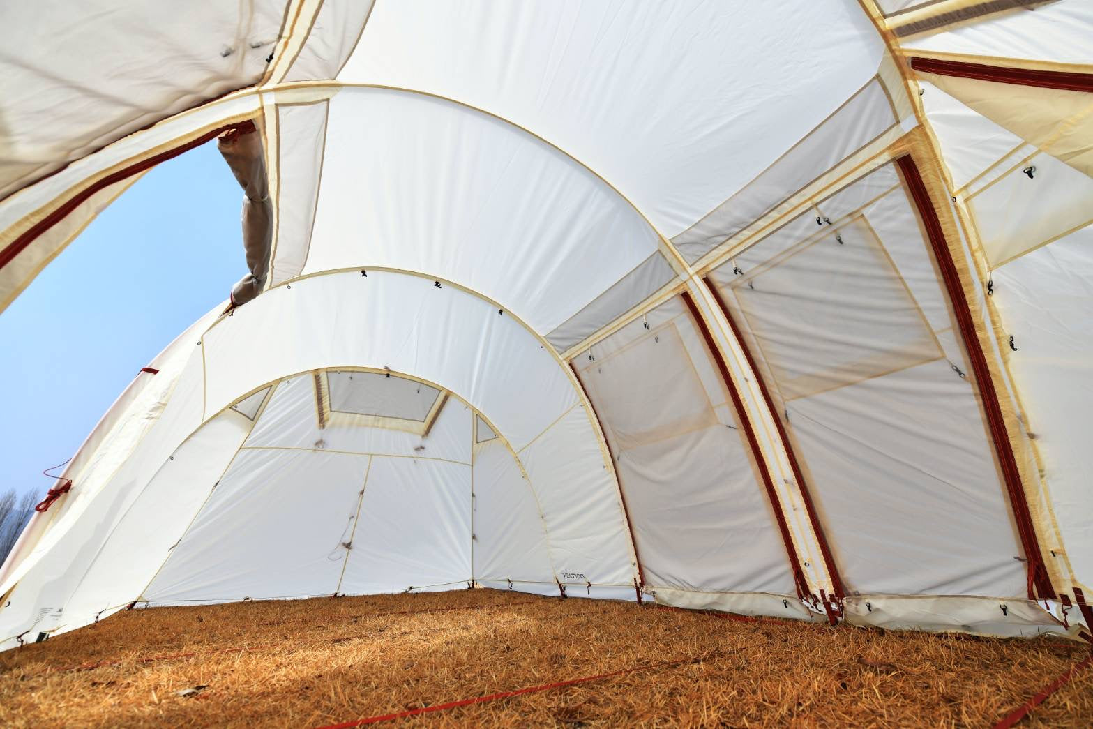 Large white fabric structure with metal frames against a blue sky.