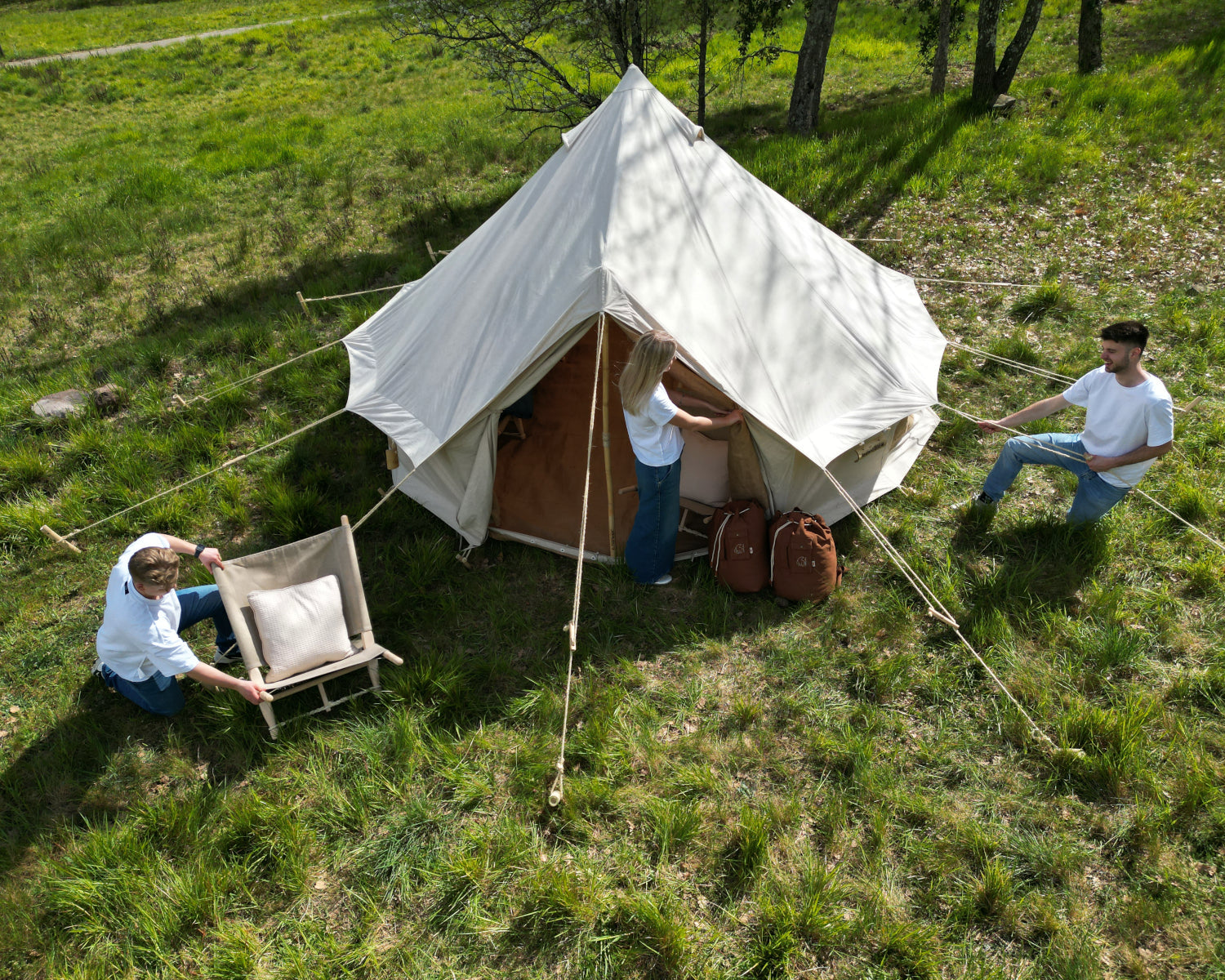 People around a large white tent in a grassy outdoor setting